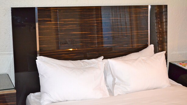 A bed with white linens and a headboard with a reflective surface. - Mogwase Bed and Breakfast (Moses Kotane)