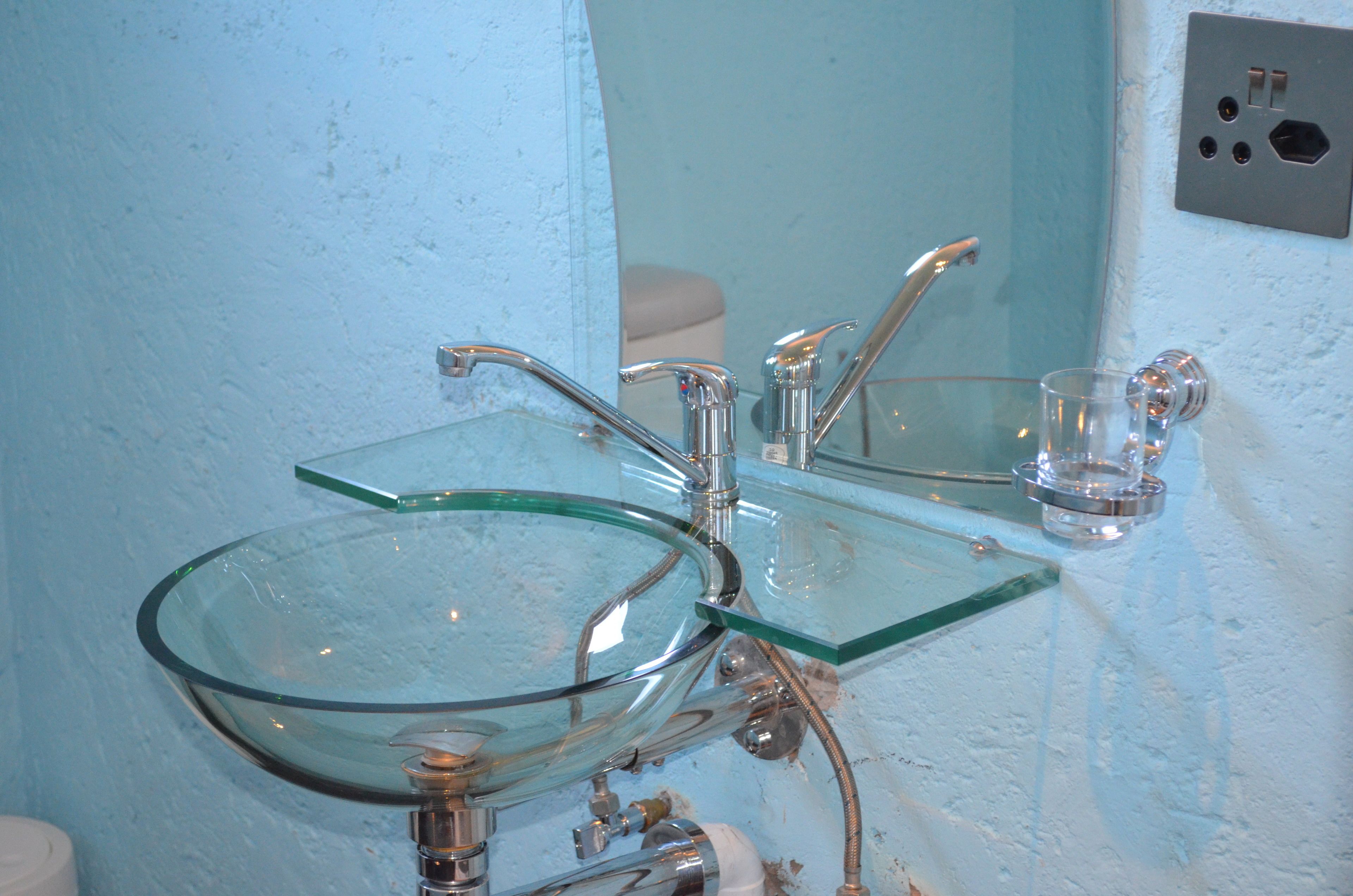 A bathroom with a glass sink and a mirror.