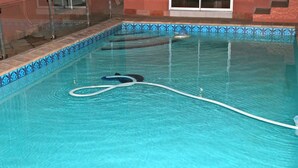 A swimming pool with clear water, a hose, and a tiled edge. - Mogwase Bed and Breakfast (Moses Kotane)