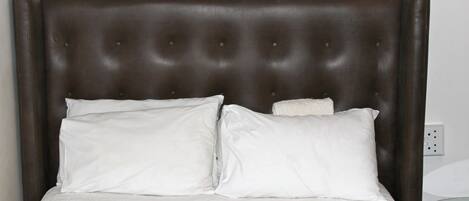 A bed with a tufted headboard, two white pillows, and a white bedspread.
