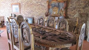 Een eettafel met ingewikkelde houtsnijwerken, omringd door stoelen met vergelijkbare ontwerpen.