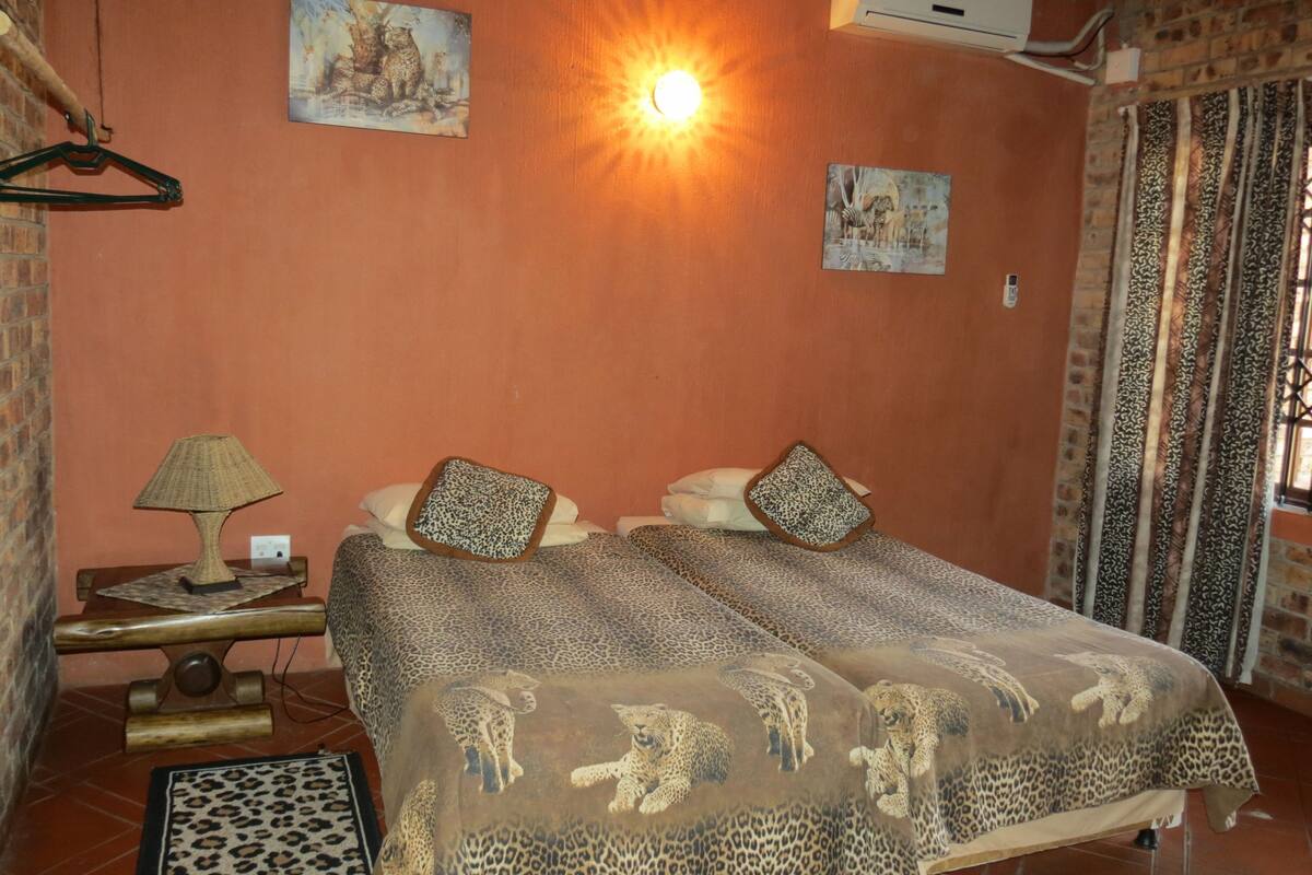 Ein Zimmer mit zwei Betten, einer Hängelampe und Bildern an den Wänden.