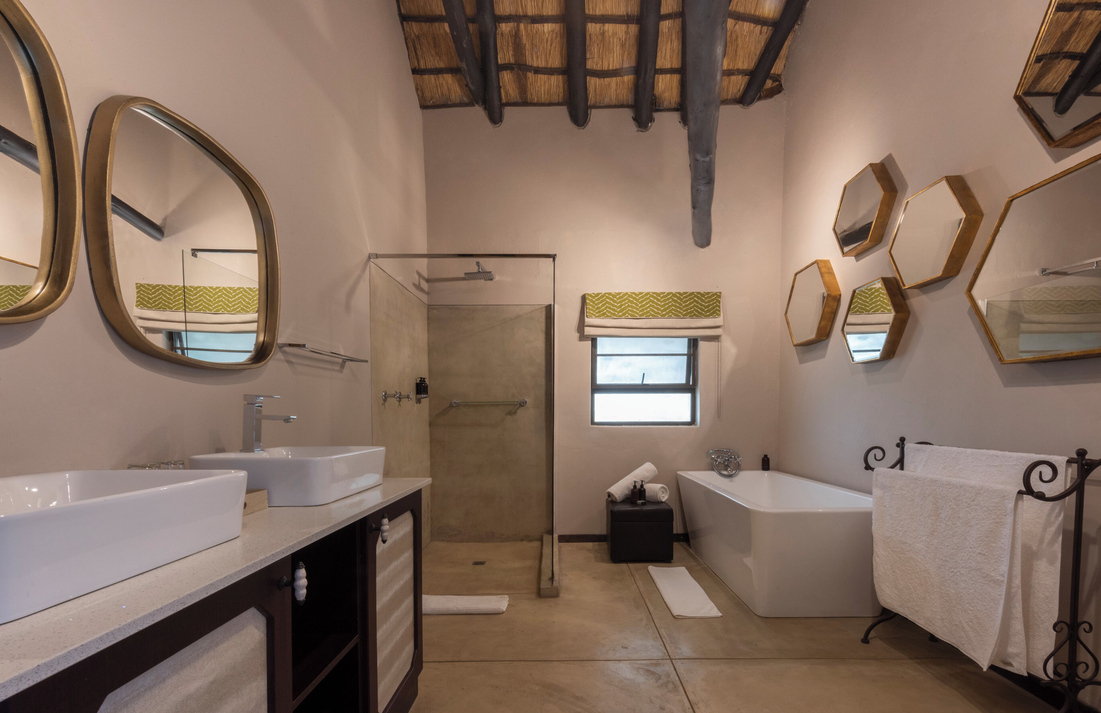 Une salle de bain avec deux lavabos, une douche, une baignoire et une fenêtre.