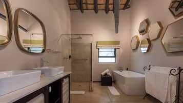 Une salle de bain avec deux lavabos, une douche, une baignoire et une fenêtre.