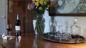 A bar area with a wine bottle, glasses, and a tray with glasses and a decanter.