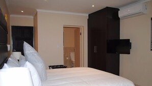 Une chambre d’hôtel avec un lit, un téléviseur fixé au mur et une armoire.