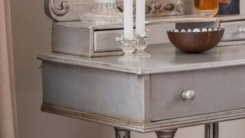 A vintage-style vanity with a mirror, two lit candles, a glass bowl, and a potted plant.