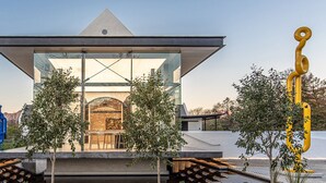A modern building with a glass facade, surrounded by trees and featuring a unique architectural design with a triangular roof. - Baruch Guest House on Rhodes Noord (Stellenbosch)
