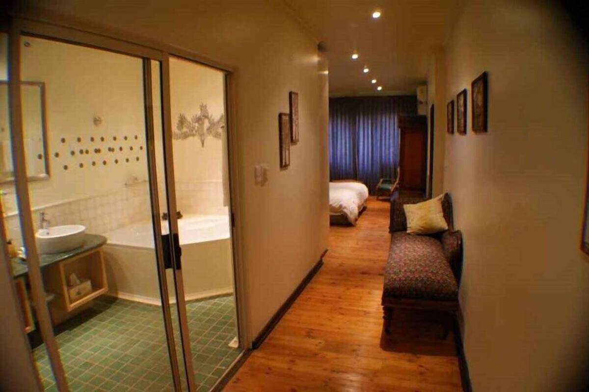A hotel room with a bathroom, a bed, a sofa, and a shower area.