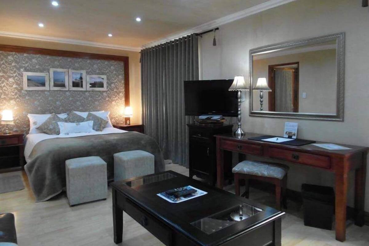 Une chambre d’hôtel équipée d’un lit, d’un bureau, d’une télévision, d’un miroir et d’une table basse.