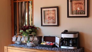 A coffee station with a coffee maker, a vase of flowers, and a framed picture on the wall. - 2 Leafed Doors (Sandton)