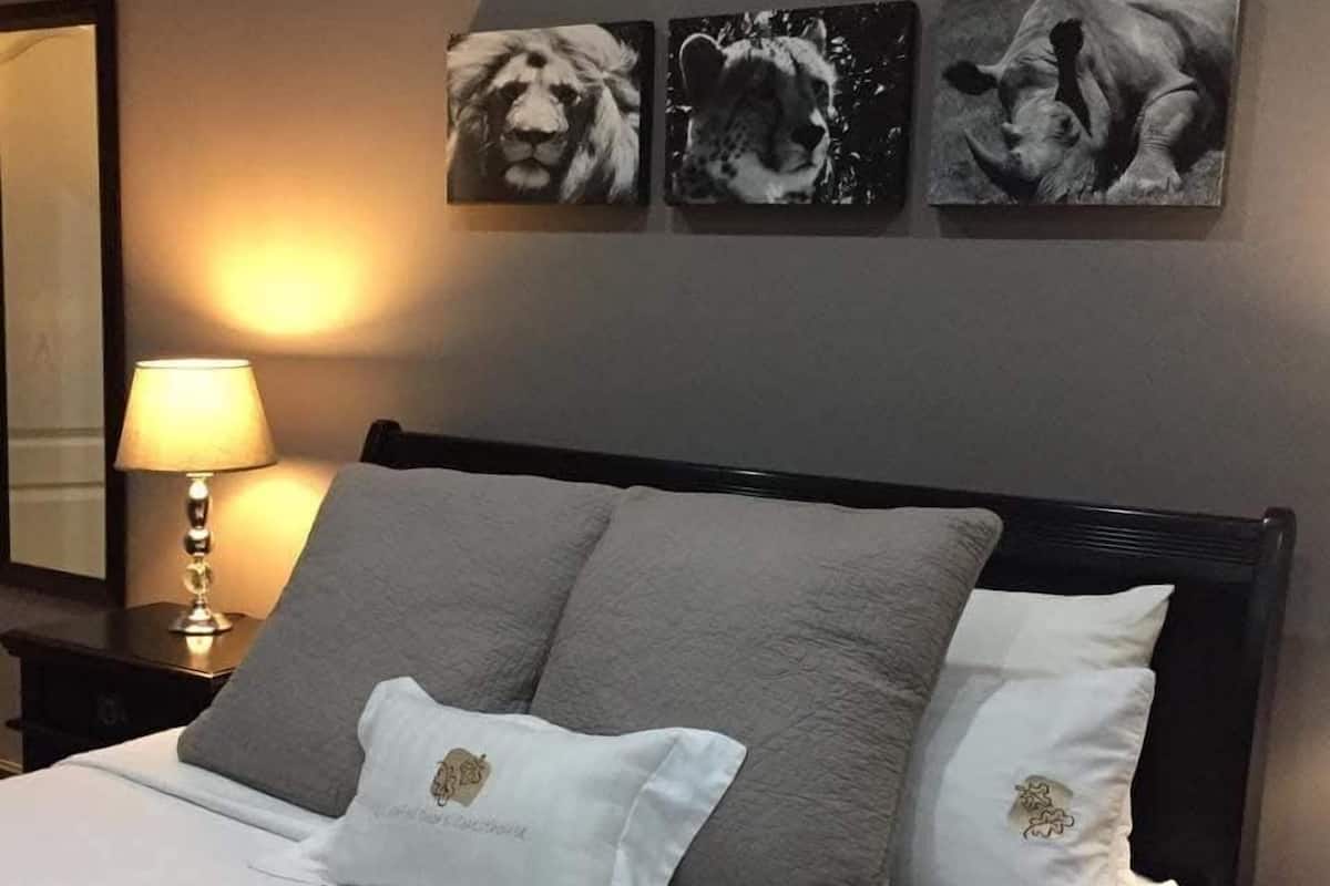 Une chambre à coucher comprenant un lit, des oreillers, une table de chevet, une lampe et trois œuvres d’art accrochées au mur.