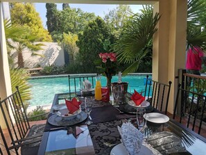 A table set for two with a view of a pool and greenery. - 2 Leafed Doors (Sandton)