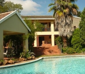 A two-story house with a swimming pool in front.