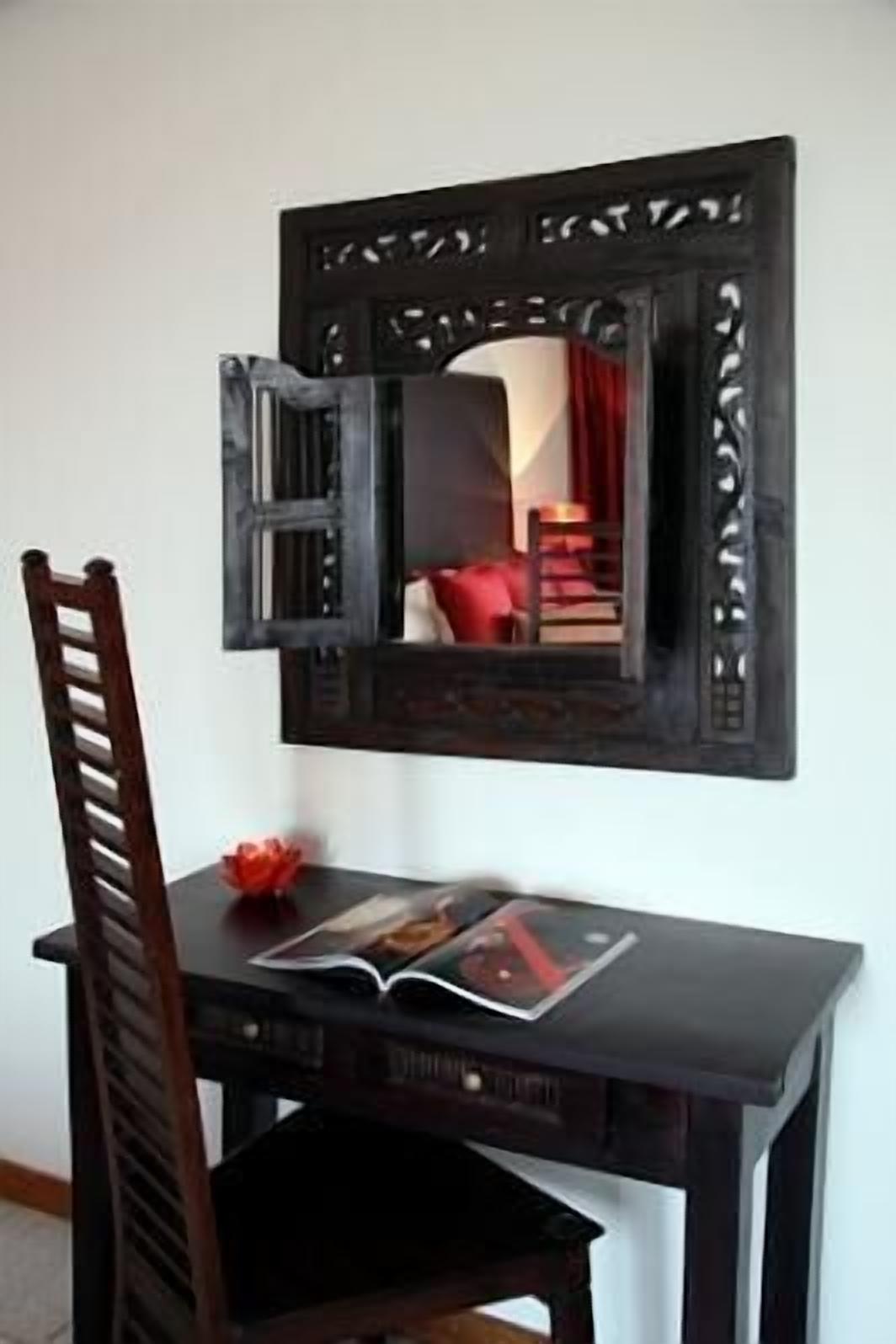 Un bureau en bois foncé, avec une chaise, un livre et un objet décoratif posé dessus.