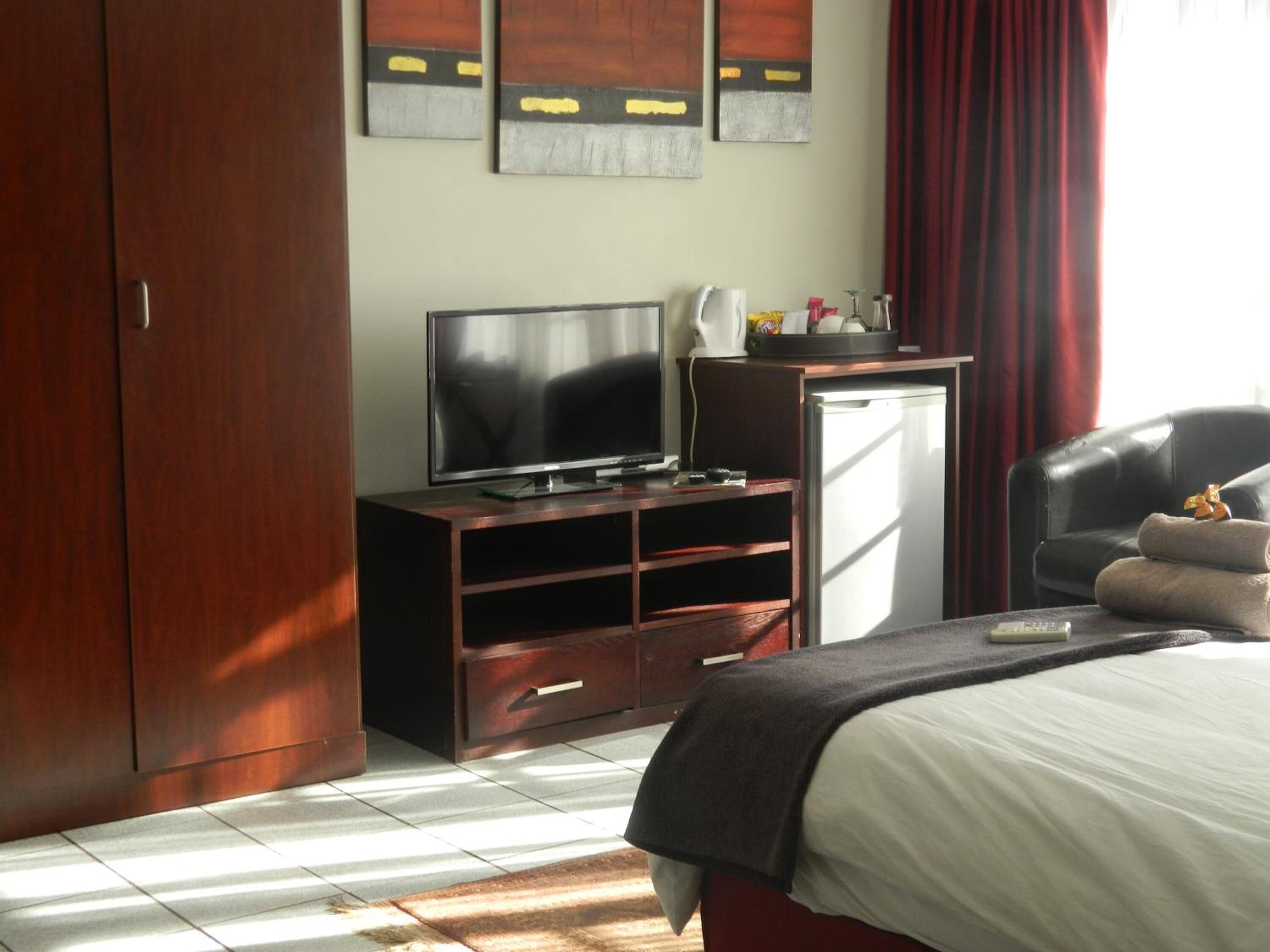 A hotel room with a bed, a TV, a desk, and a wardrobe.