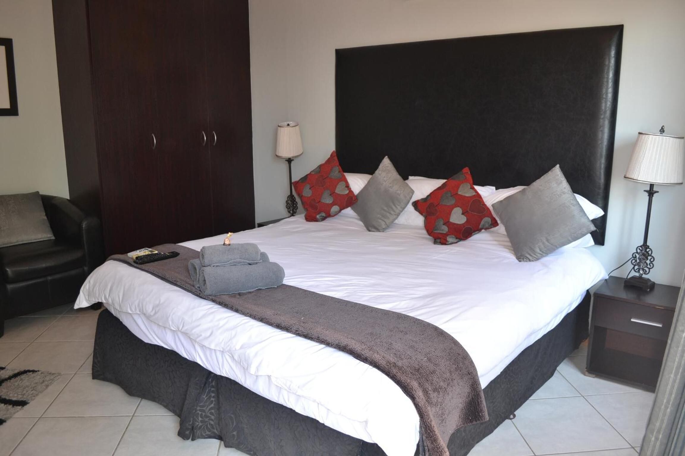 A neatly made bed with a dark headboard, multiple pillows, and a blanket.
