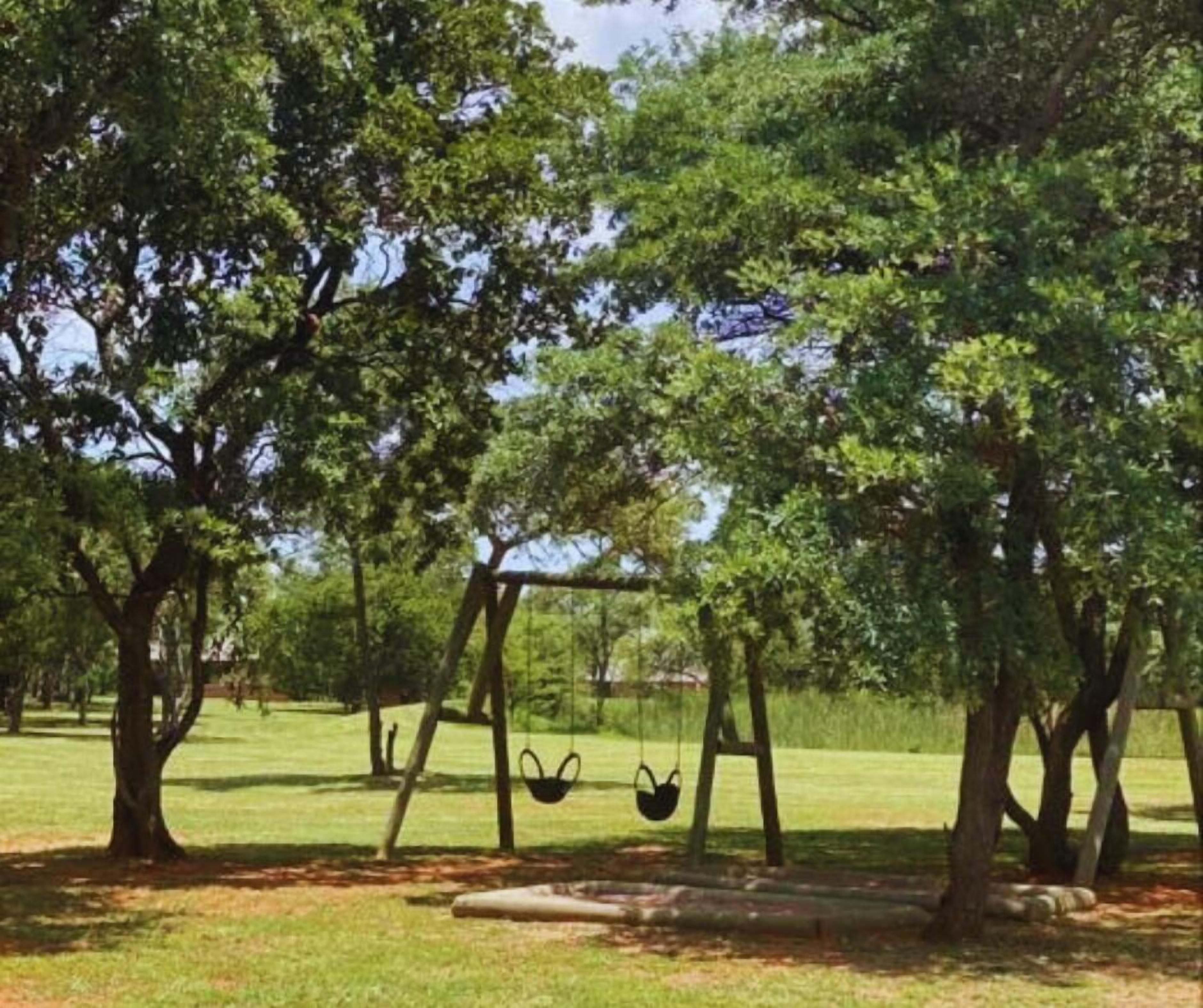 Un parque con columpios y árboles.