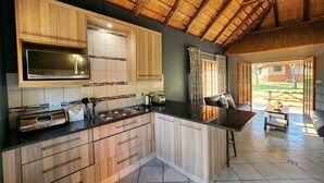Cocina moderna con armarios de madera, encimera negra y techo con tejado de paja.