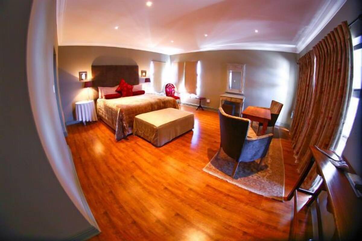 A spacious hotel room with a large bed, a desk, and a chair.