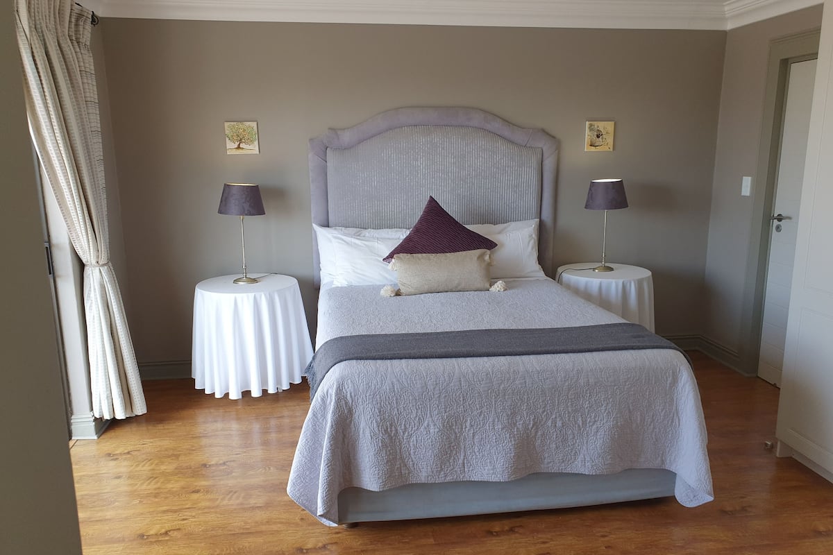 A neatly arranged bedroom with a large bed, two bedside tables, and a headboard.