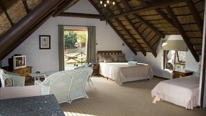 A cozy attic bedroom with a sloped ceiling, two beds, a small table, and a chair. - Tides Lodge (Malagas)