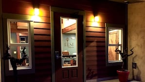 L’entrée d’un hôtel de charme, avec une façade en bois, une porte en verre et un paillasson.