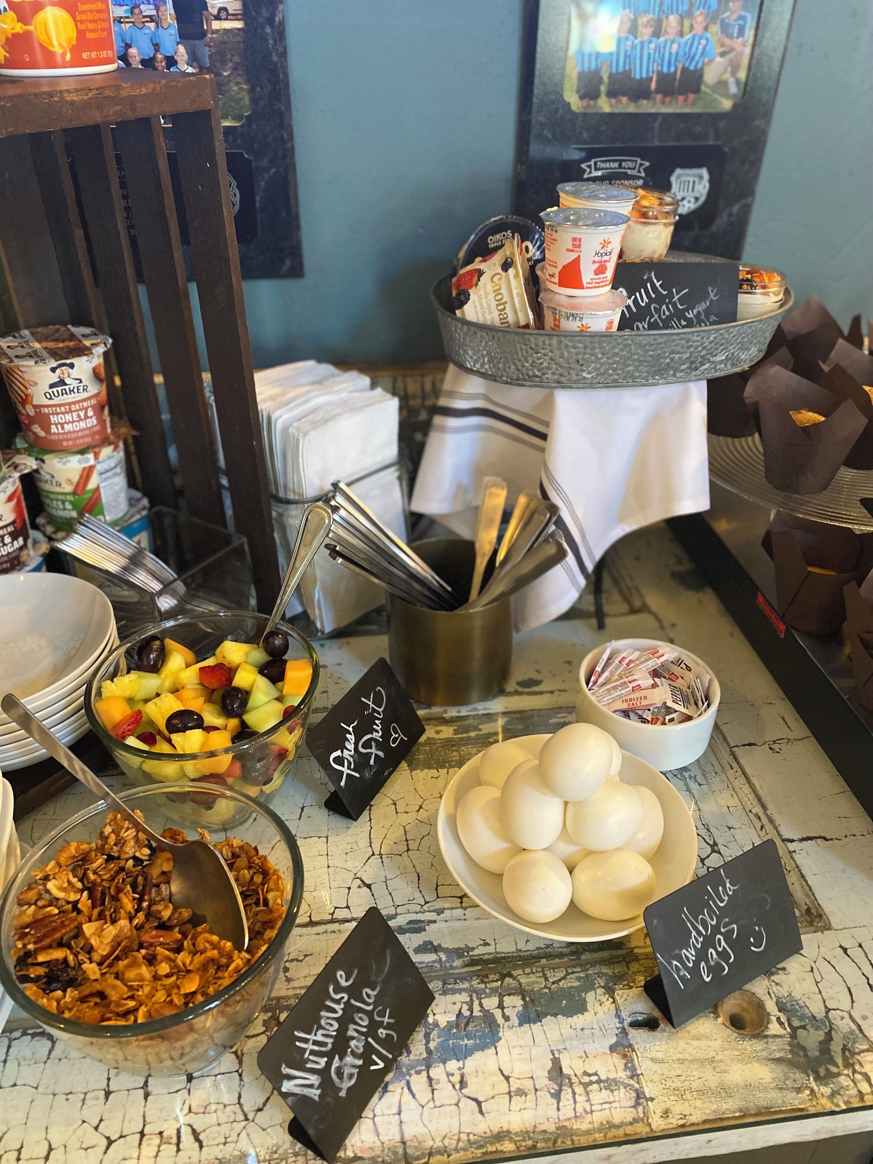A breakfast buffet with various food items including fresh fruit, granola, eggs, and cereal.