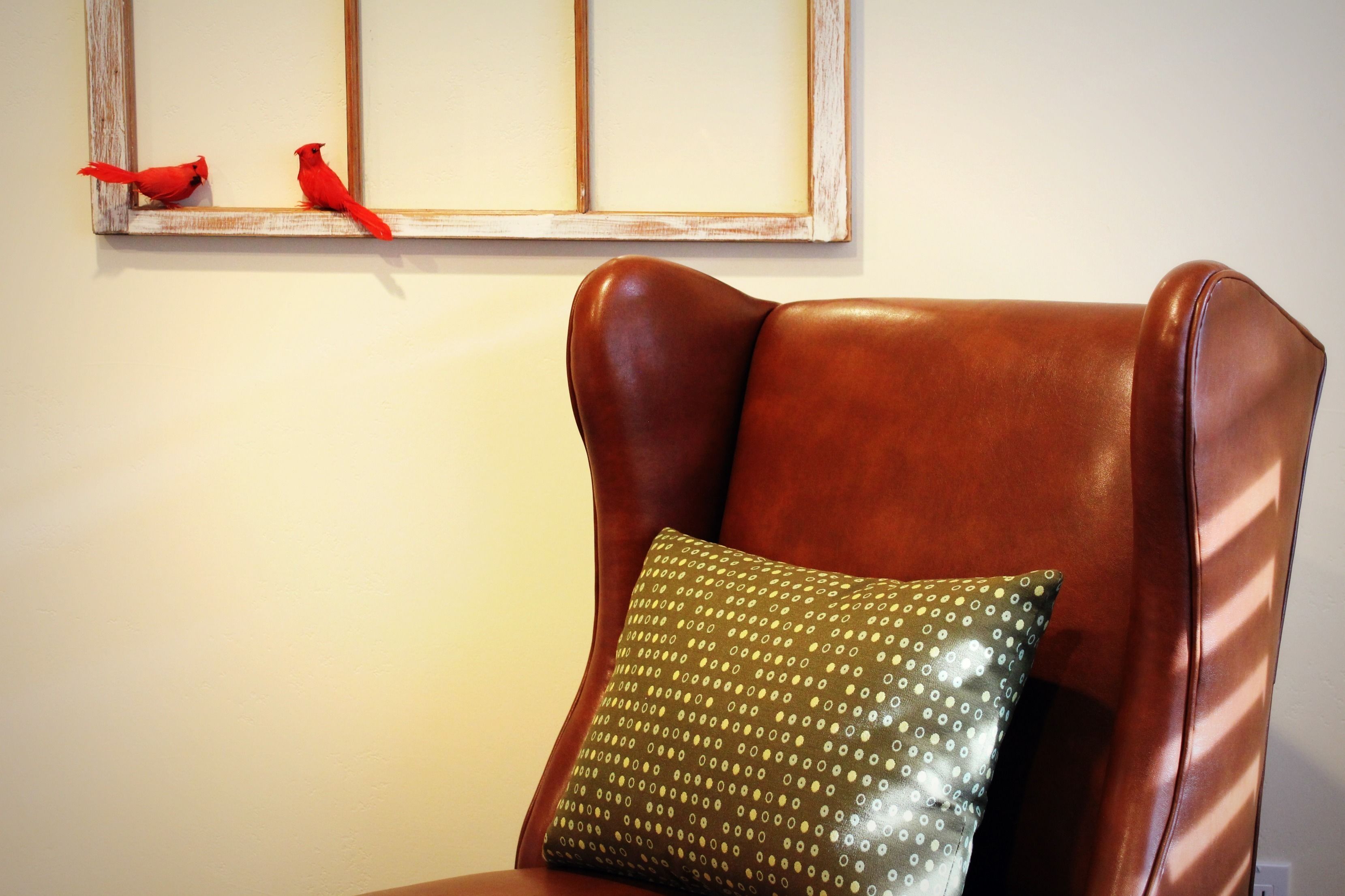 A brown leather armchair with a green pillow.