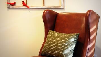 A brown leather armchair with a green pillow.