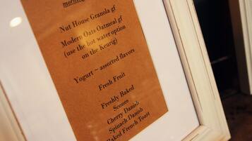 A framed menu listing breakfast options including Nut House Granola, Modern Oats Oatmeal, Yogurt, Fresh Fruit, Freshly Baked Scones, Cherry Danish, and Baked French Toast.