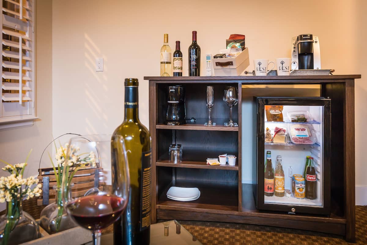 Una cocina con refrigerador, botellas de vino y cafetera.