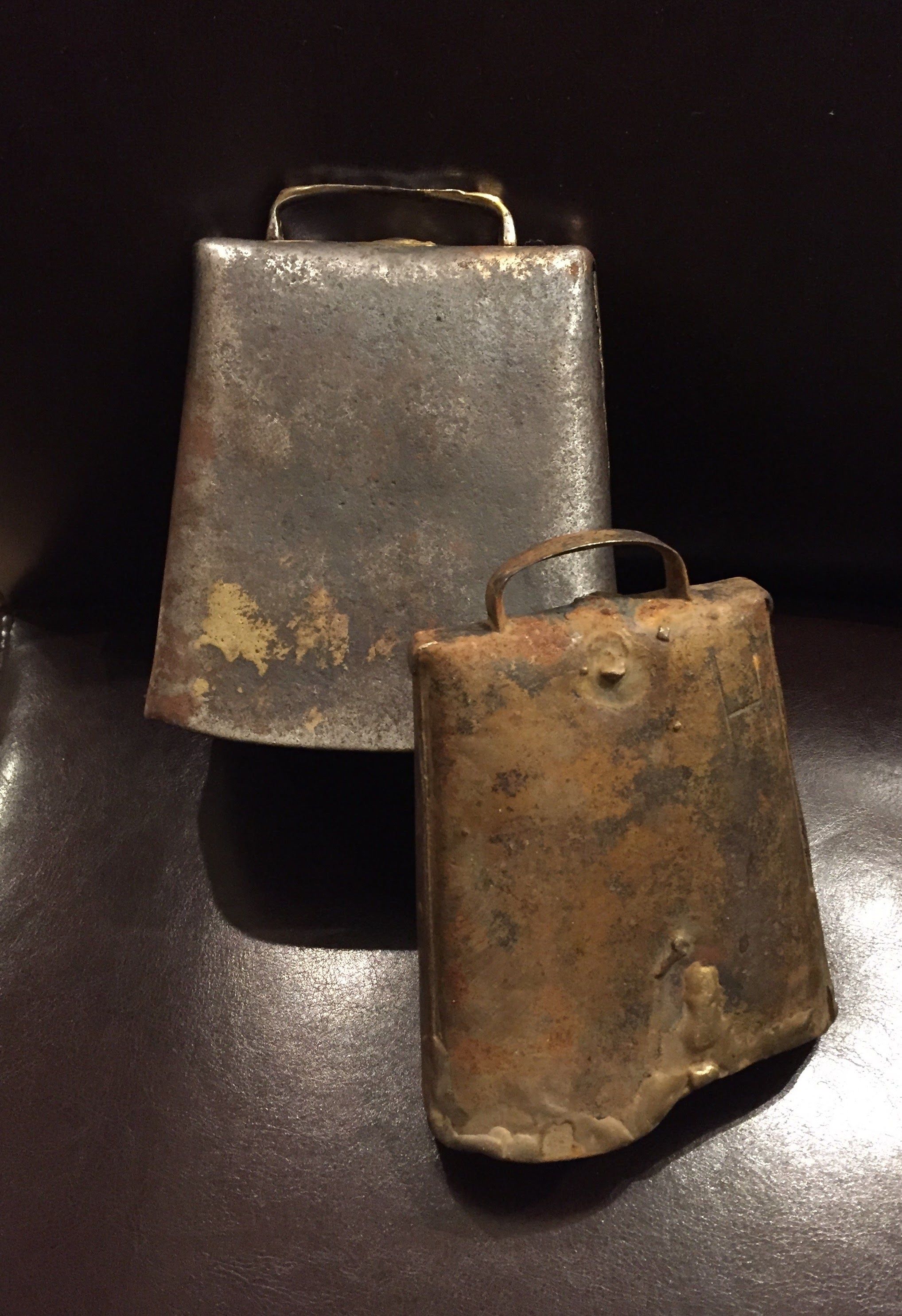 Two metal containers with handles, one larger than the other, placed on a dark surface.