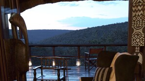 Cómoda sala de estar con un gran ventanal que ofrece una vista panorámica, amueblada con un sillón, reposapiés y elementos decorativos.