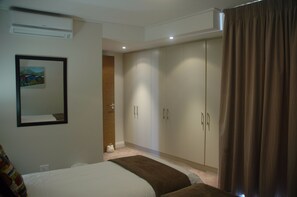 A hotel room with a bed, a wardrobe, and a painting on the wall. - 501 Canal Quays (Cape Town)
