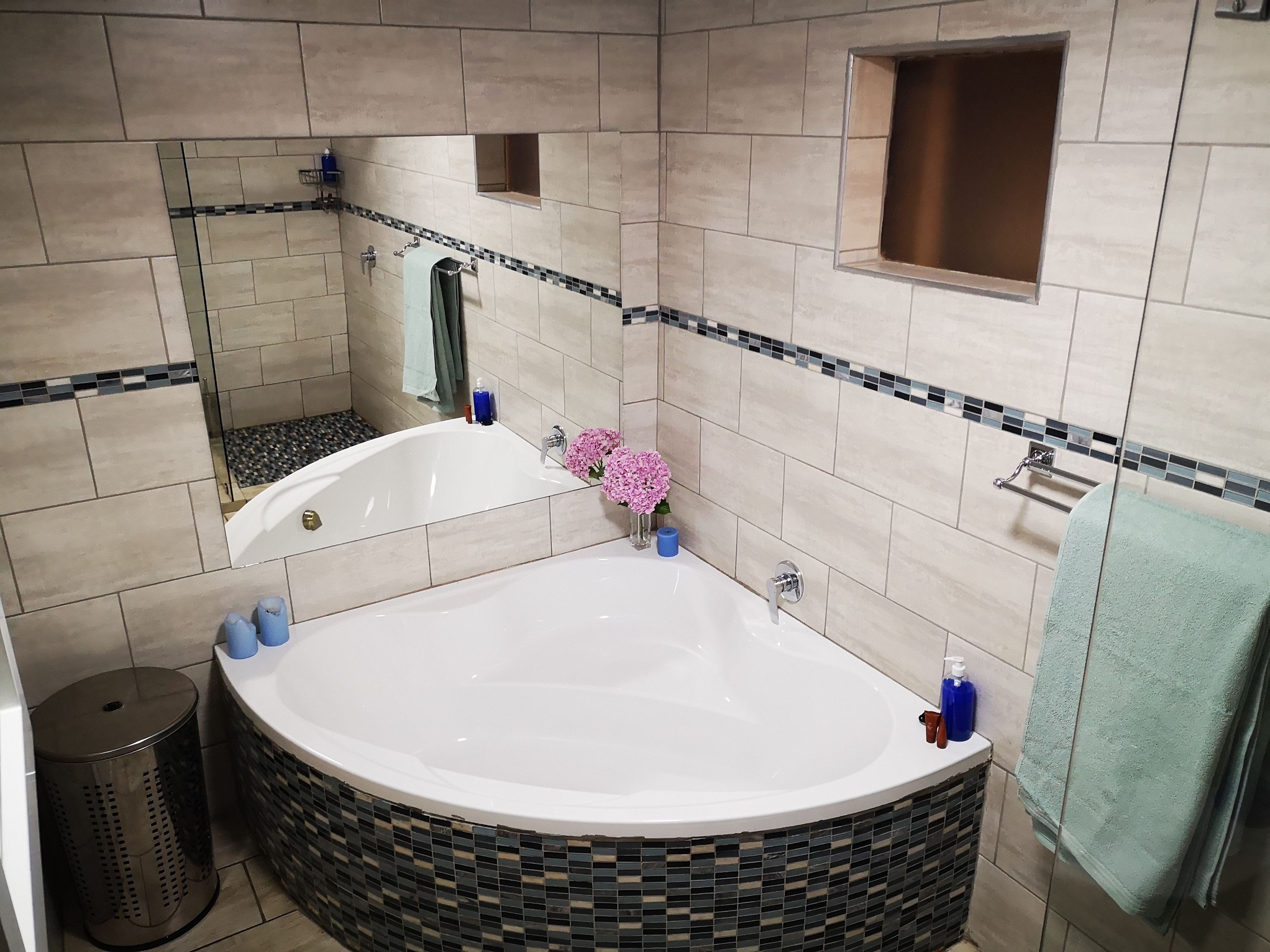 Un baño moderno con una bañera independiente, un espejo y una zona de ducha con azulejos.