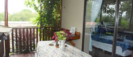 Un balcon avec une table, une chaise et un pot de fleurs.
