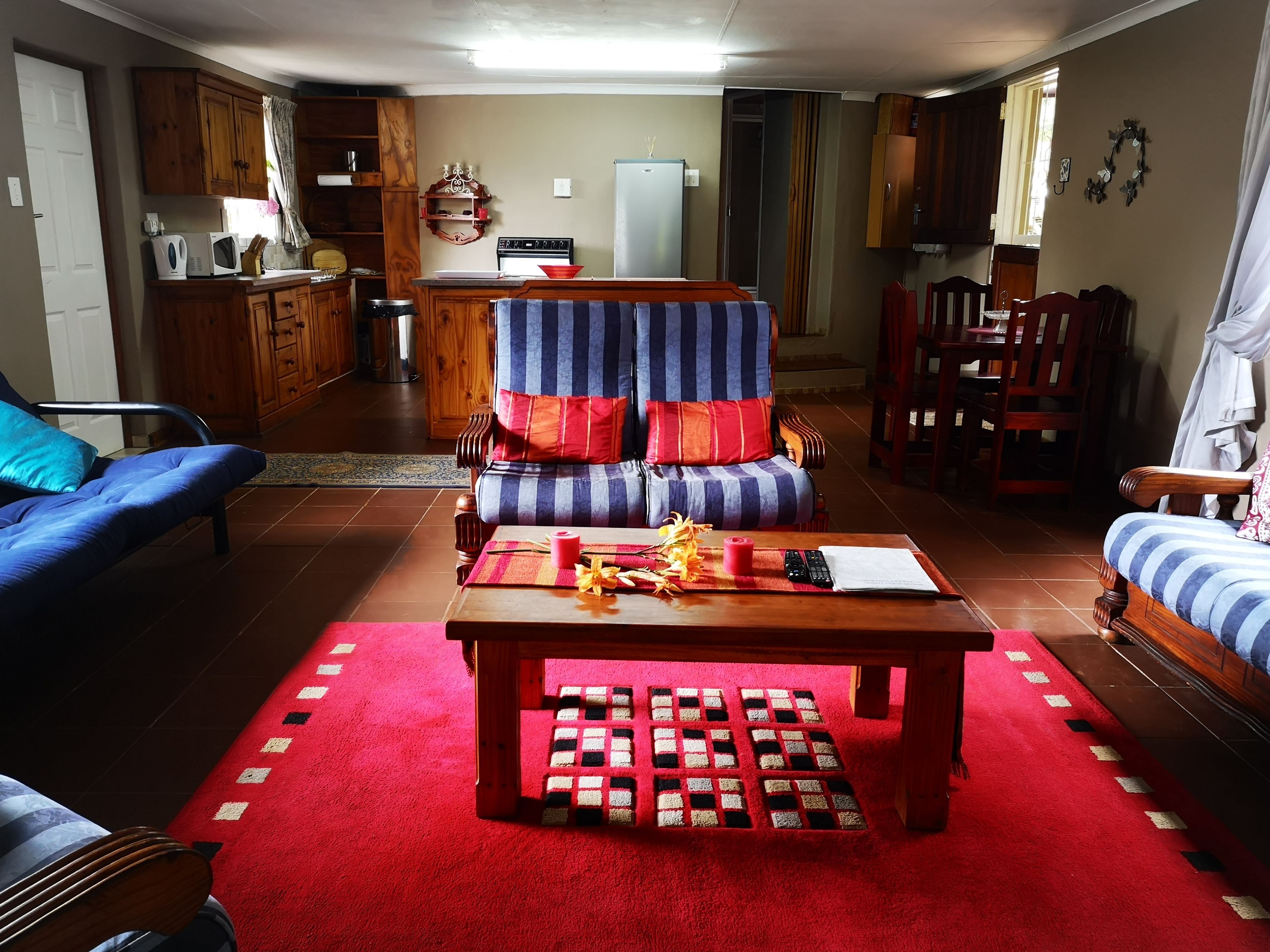 A living room with a sofa, armchair, and a coffee table with a red rug.