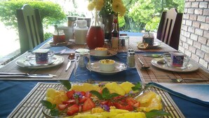 Een ontbijttafel gedekt met borden, bestek en een fruitschaal.