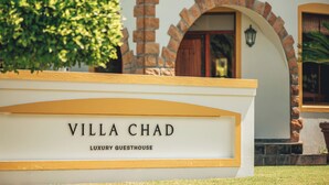 A sign for Villa Chad, a luxury guesthouse, with a brick archway and a well-maintained lawn. - Villa Chad Luxury Guesthouse (Kleinmond)