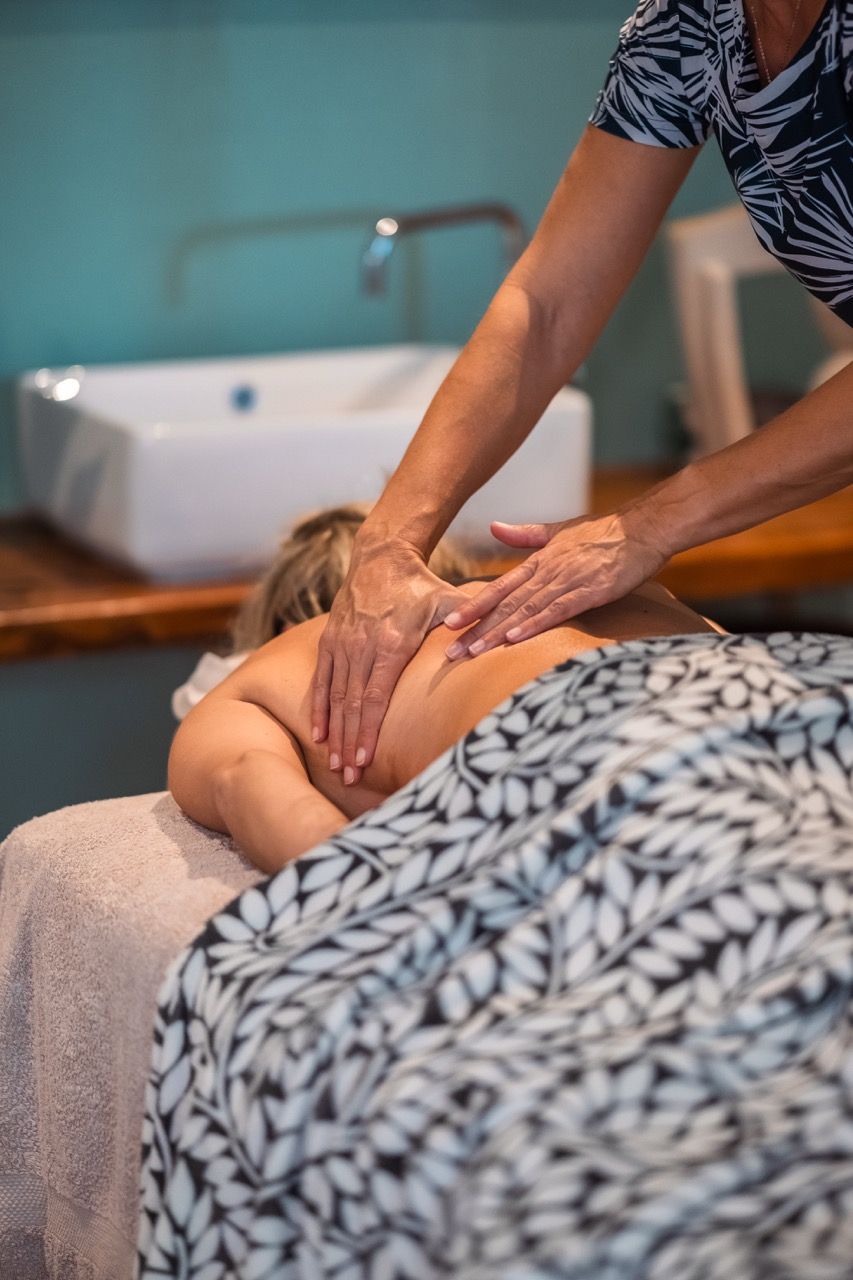 Une séance de massage dans une pièce équipée d’un lavabo et d’une table de massage recouverte d’une serviette.