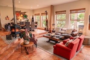 A spacious living room with a fireplace, comfortable seating, and large windows. - Villa Chad Luxury Guesthouse (Kleinmond)