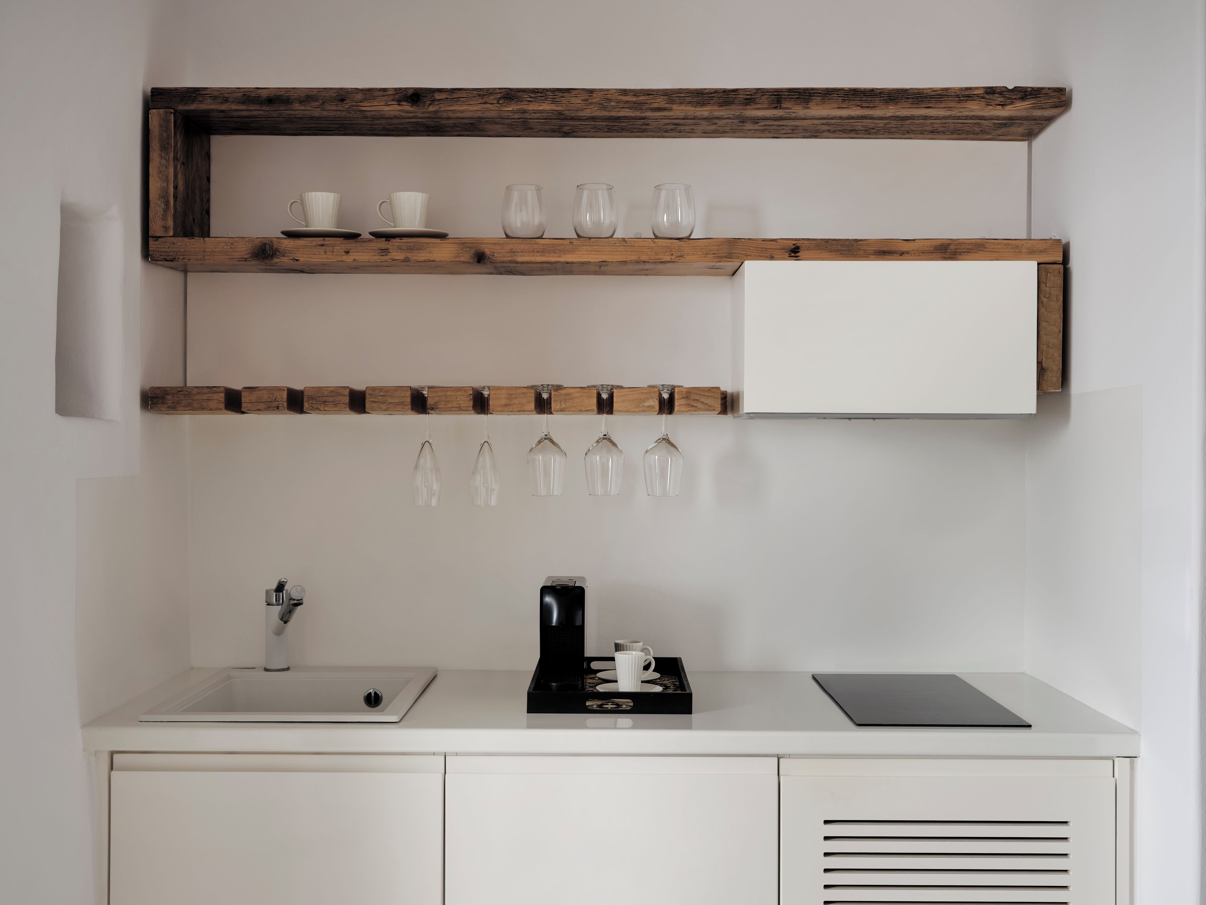 A kitchen with wooden shelves, a coffee maker, and a sink.