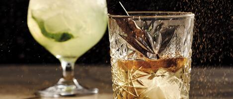 Two glasses of beverages on a table with a dark background.