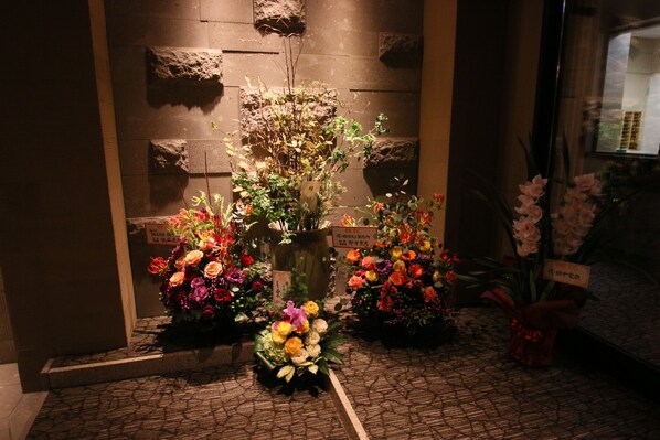 A flower arrangement in front of a building with a stone wall and a window. - Furano Shiyuirin (Kamifurano)