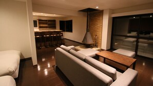 A modern living room with a sofa set, a wooden coffee table, and a bar area in the background. - Furano Shiyuirin (Kamifurano)