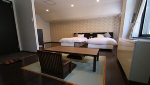 A hotel room with a wooden dining table, two beds, a small kitchenette, and a dark wooden floor. - Furano Shiyuirin (Kamifurano)