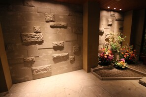 A stone wall with a recessed area containing colorful flowers.