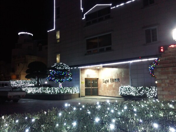 A hotel entrance with a sign reading "Light House" and illuminated trees and bushes.