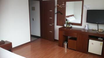 Una habitación de hotel con un escritorio de madera, un espejo, un televisor y un refrigerador pequeño.